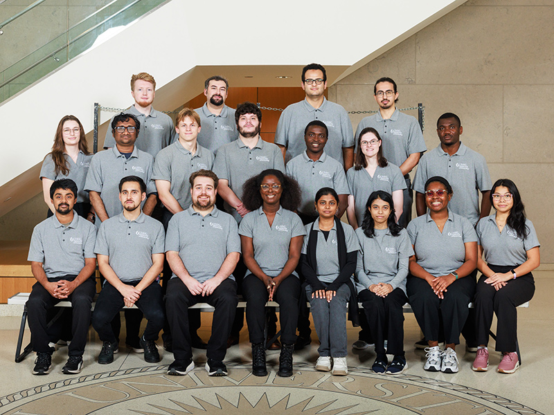Group portrait of graduate students in the lobby of the School of Medicine. A staircase is behind them.